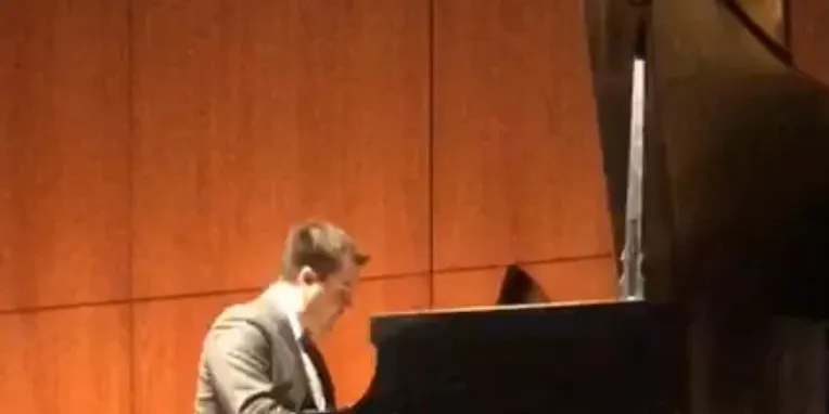 Chris playing a grand piano on stage